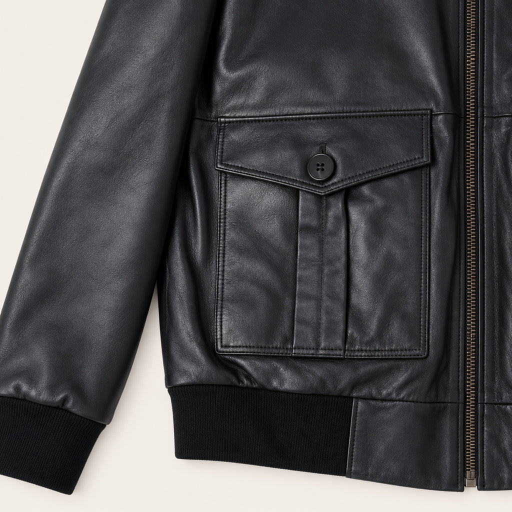 Black Bomber Jacket, close-up detail on an ivory studio background.