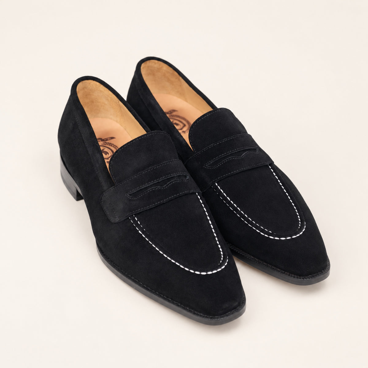Black Suede Penny Loafers, three-quarter front view on an ivory studio background.